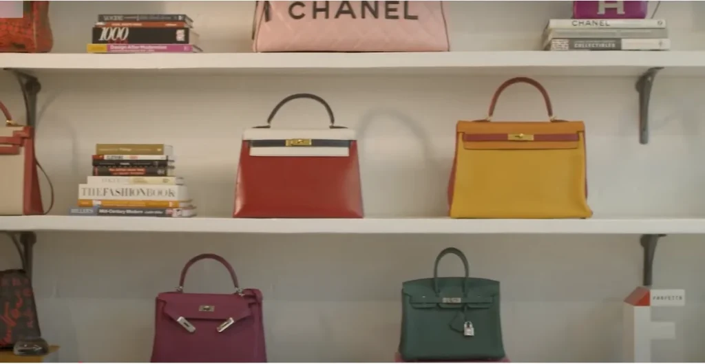 "Generate a high-quality image of a collection of stylish handbags displayed on a luxurious marble surface. The handbags come in various shapes, sizes, and colors, including leather, suede, and quilted textures. Some feature gold or silver chain straps, while others have elegant top handles. The background is softly lit with a modern, minimalist aesthetic, emphasizing the sophistication and elegance of the handbags. The composition should be visually appealing, highlighting fine details like stitching, clasps, and designer logos."